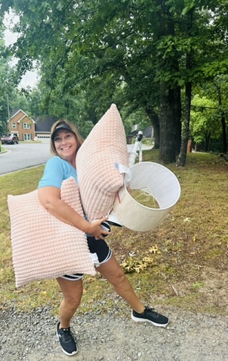 A volunteer carrying a donated lamp shade and pillows for SELL Co.