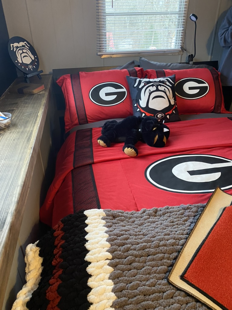 Completed Georgia-themed RRGA bedroom with red University of Georgia bedding, a bulldog pillow and plush toy on the bed.